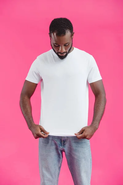 Retrato de homem afro-americano olhando para camisa branca isolada em rosa — Fotografia de Stock