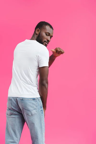 Вид ззаду афроамериканця, який вказує на порожню білу сорочку ізольовано на рожевому — стокове фото