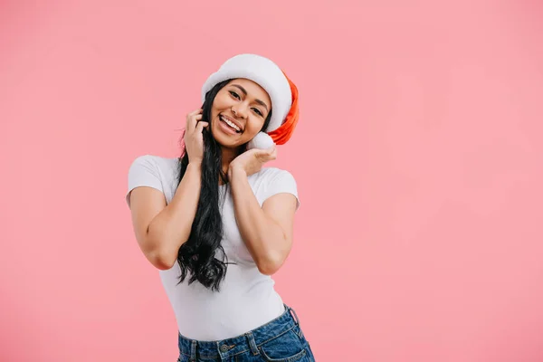 Ritratto di felice donna afroamericana in cappello di Babbo Natale isolato su rosa — Foto stock