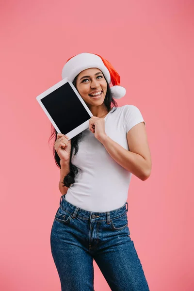 Portrait of happy african american woman in santa claus hat with tablet with blank screen isolated on pink — Stock Photo