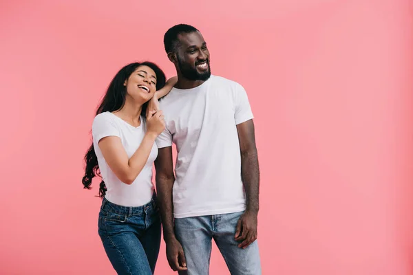 Улыбающаяся молодая африканская американская пара смотрит в сторону изолированных на розовом фоне — стоковое фото