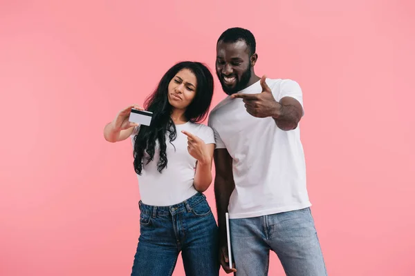 Emocional casal afro-americano apontando para cartão de crédito isolado em fundo rosa — Fotografia de Stock