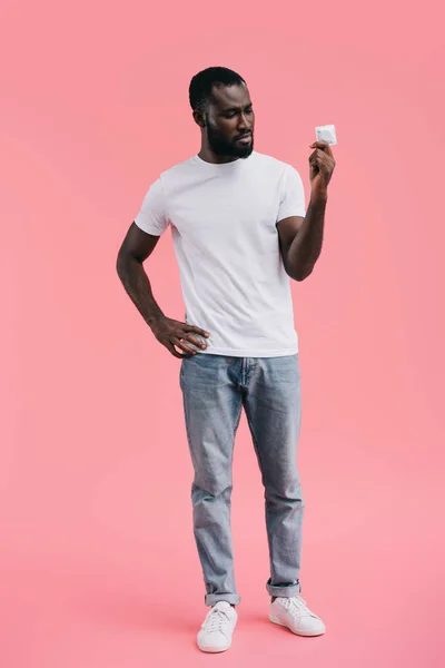 Jeune homme afro-américain avec préservatif isolé sur fond rose — Photo de stock