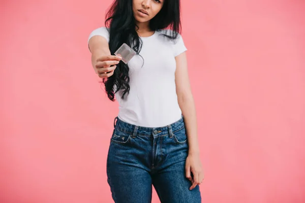 Vista parcial de una joven afroamericana mostrando condón aislado sobre fondo rosa - foto de stock