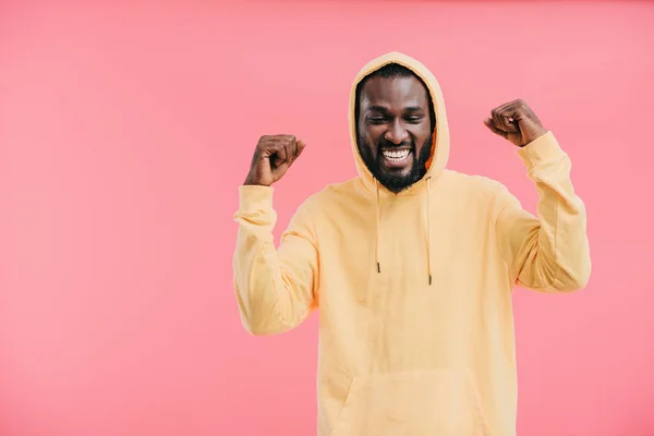 Смеющийся африканский американец с поднятыми руками на розовом фоне — стоковое фото