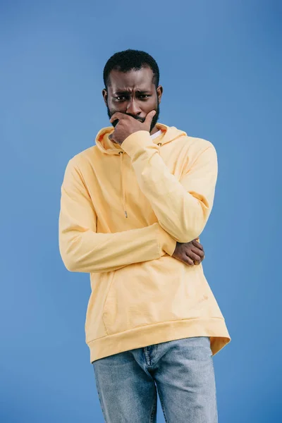 Inquiet jeune homme afro-américain avec la main sur le menton solitaire sur fond bleu — Photo de stock