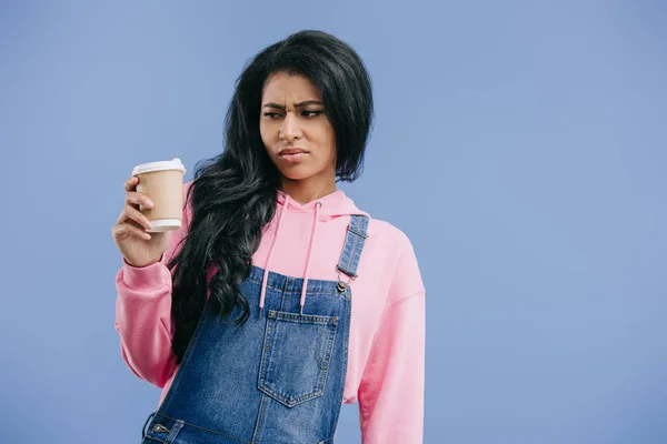 Molesto joven afroamericana mujer con taza de café desechable aislado sobre fondo azul - foto de stock