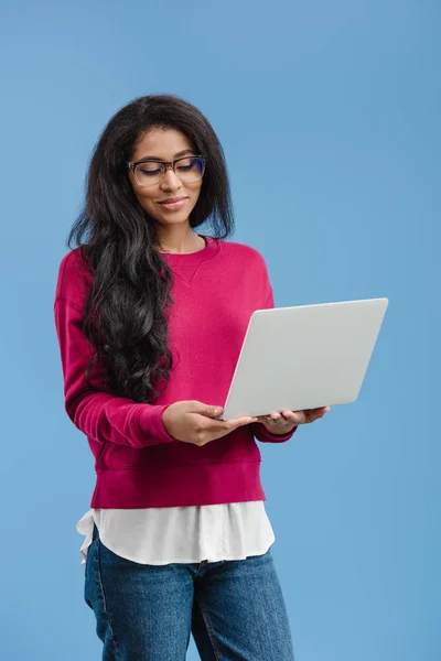 Feliz mulher americana africana em óculos segurando laptop isolado no fundo azul — Fotografia de Stock