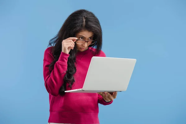 Focused young african american woman in eyeglasses looking at laptop isolated on blue background — Stock Photo