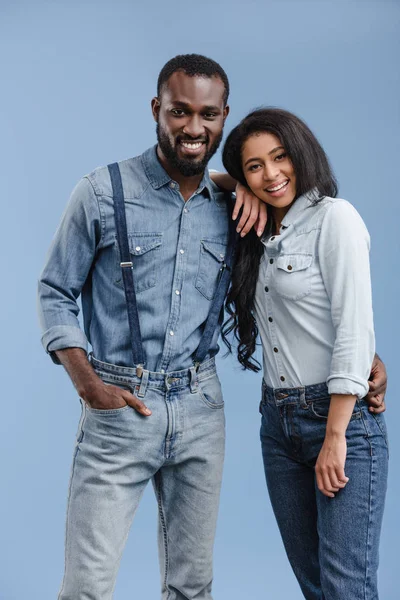 Feliz africano americano pareja abrazando y mirando la cámara aislado en azul - foto de stock