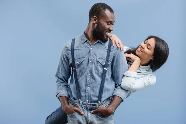 Smiling african american couple hugging and looking at each other isolated on blue — Stock Photo