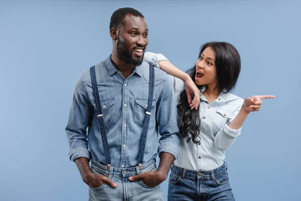 Sorprendido afroamericano novia apuntando en algo a novio aislado en azul - foto de stock