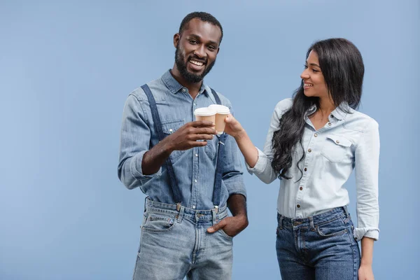 Sorridente coppia afroamericana clinking con caffè in tazze di carta isolato su blu — Foto stock