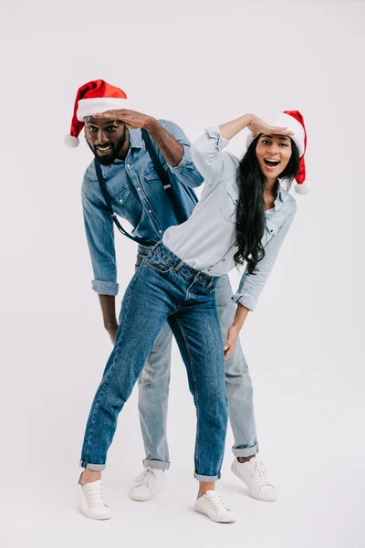 Couple afro-américain chapeaux Santa avoir du plaisir et à la recherche de quelque chose d'isolé sur blanc — Photo de stock