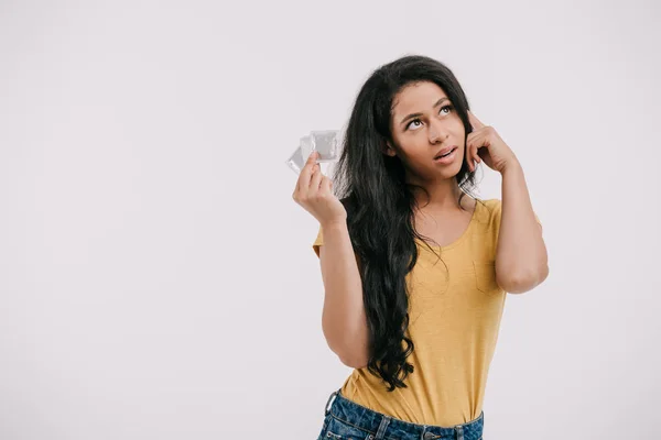 Pensivo atraente afro-americano menina segurando preservativos de látex e olhando para cima isolado no branco — Fotografia de Stock
