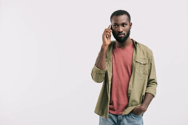 Hombre afroamericano guapo serio hablando por teléfono inteligente aislado en blanco - foto de stock