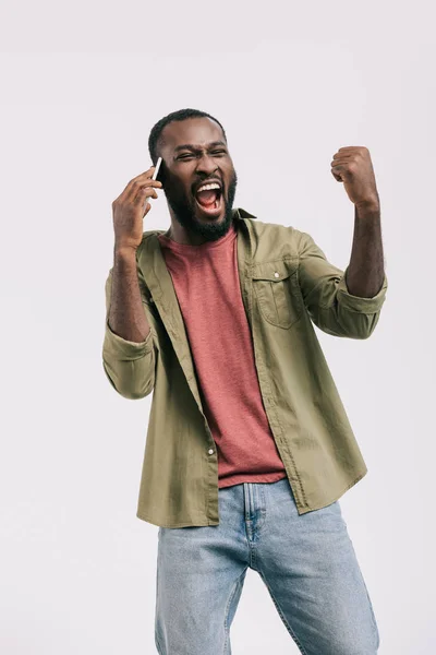 Excited african american man talking by smartphone and showing yes gesture isolated on white — Stock Photo