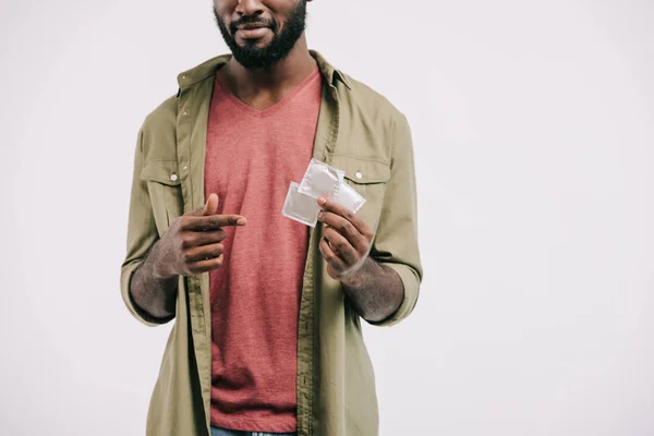Imagem recortada do homem afro-americano apontando sobre preservativos isolados em branco — Fotografia de Stock