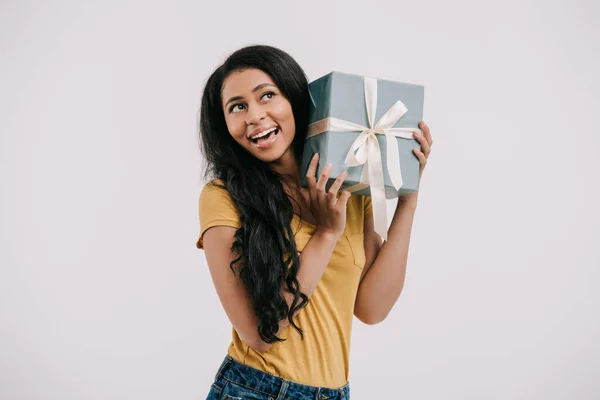 Sorridente ragazza afroamericana ascolto scatola presente isolato su bianco — Foto stock