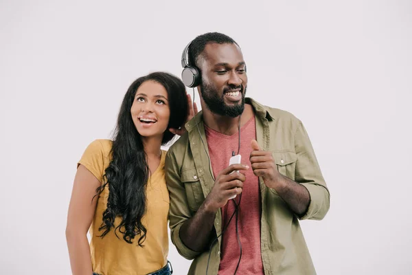 Happy african american girlfriend eavesdropping boyfriend music isolated on white — Stock Photo