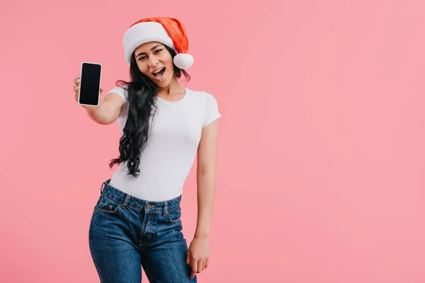 Excited attractive african american girl in sants hat showing smartphone with blank screen isolated on pink — Stock Photo