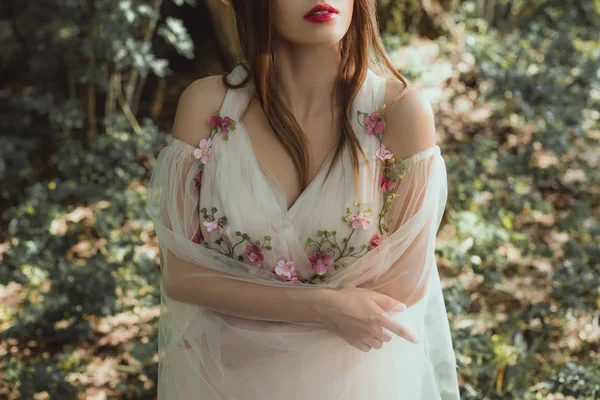 Обрезанный вид красивой девушки в платье с цветами стоя со скрещенными руками — стоковое фото