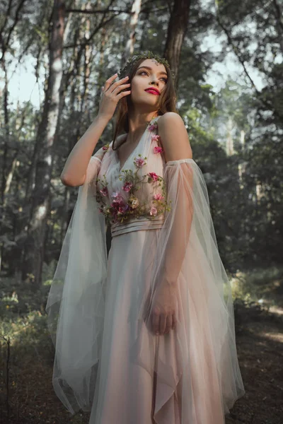 Elfo místico atractivo en vestido de flores en el bosque - foto de stock