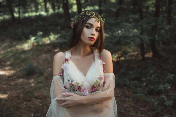 Attraktive Elfenfrau in Kleid und Blumenkranz im Wald — Stockfoto