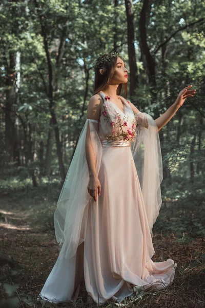 Mystic elf in character in flower dress walking in woods — Stock Photo