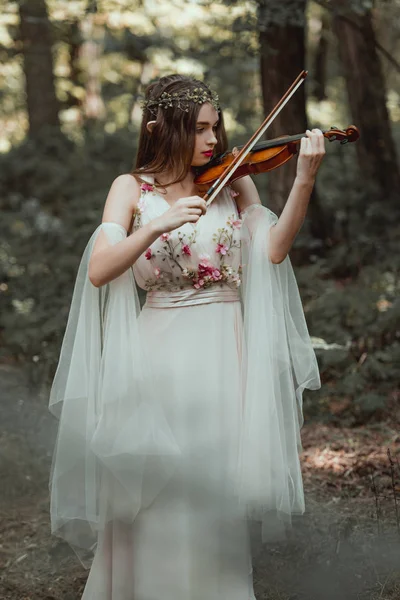 Hermoso elfo místico tocando el violín en el bosque - foto de stock