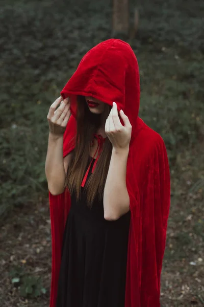 Femme mystique en manteau rouge et capuche dans les bois sombres — Photo de stock