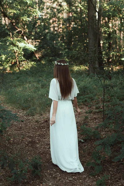 Back view of girl in white elegant dress walking in forest — Stock Photo