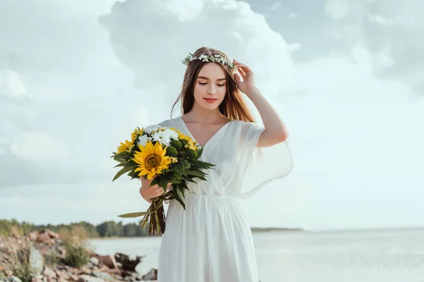 Bella ragazza elegante in abito bianco che tiene mazzo di fiori — Foto stock