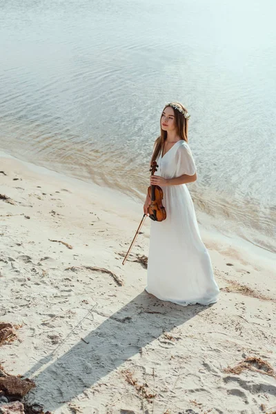 Hübsches Mädchen im eleganten Kleid mit Geige am Strand — Stockfoto
