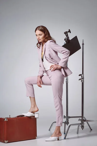 Bella donna alla moda in posa con valigia e guardando lontano in studio di registrazione — Foto stock