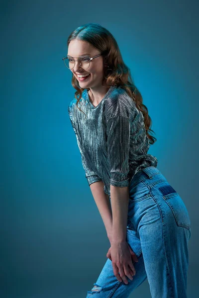 Hermosa mujer sonriente en traje elegante riendo y mirando hacia otro lado aislado en azul - foto de stock