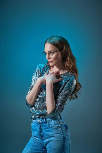 Hermosa mujer en traje elegante y anteojos mirando hacia otro lado aislado en azul - foto de stock