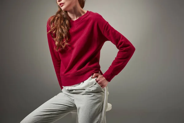 Cropped shot of young woman in stylish outfit sitting on stool isolated on grey — Stock Photo