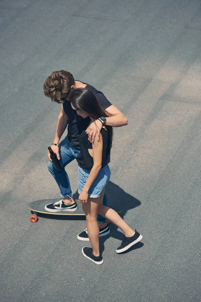 Jovem casal abraço e skate no longboard — Fotografia de Stock