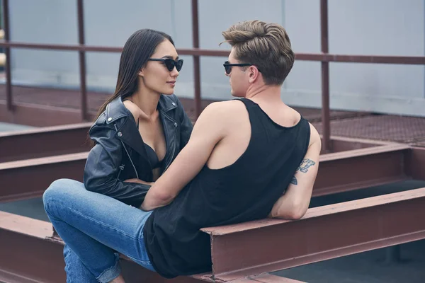 Multiétnico elegante sexy pareja en gafas de sol mirando el uno al otro - foto de stock