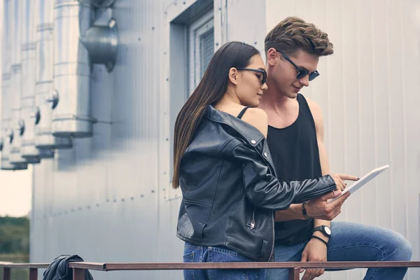 Межрасовая молодая пара в солнечных очках с помощью цифрового планшета — стоковое фото