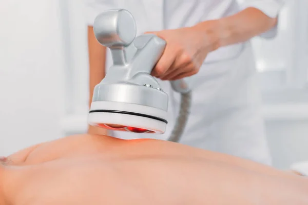 Cropped shot of woman on massage table getting electrical massage done by cosmetologist in spa salon — Stock Photo