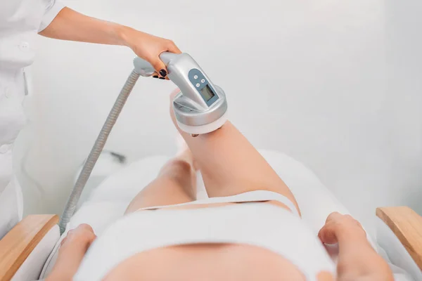 Cropped shot of cosmetologist making electrical massage to female client in white underwear in spa salon — Stock Photo