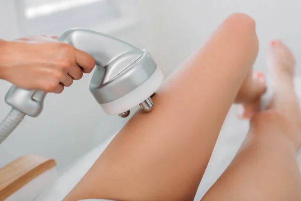 Abgeschnittene Aufnahme eines Kosmetikers, der einer Kundin in weißer Unterwäsche im Wellness-Salon elektrische Massage ermöglicht — Stockfoto