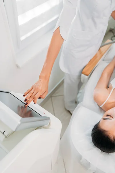 Cropped shot of cosmetologist making electrical massage to female client in white underwear in spa salon — Stock Photo