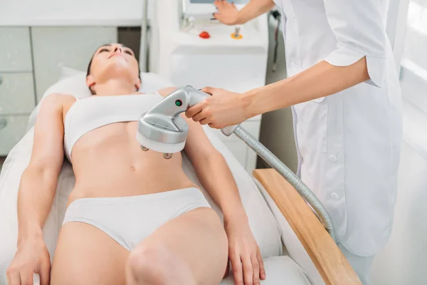 Atractiva mujer recibiendo masaje eléctrico hecho por el cosmetólogo en el salón de spa - foto de stock