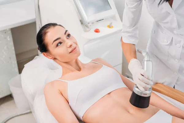 Atractiva mujer recibiendo masaje eléctrico hecho por el cosmetólogo en el salón de spa - foto de stock