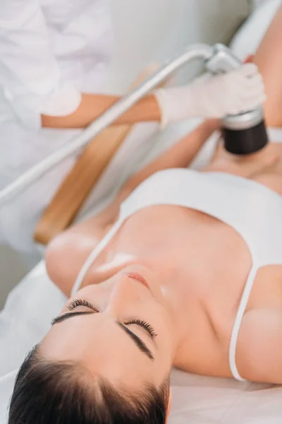 Partial view of cosmetologist making electric massage to woman in white underwear at spa salon — Stock Photo
