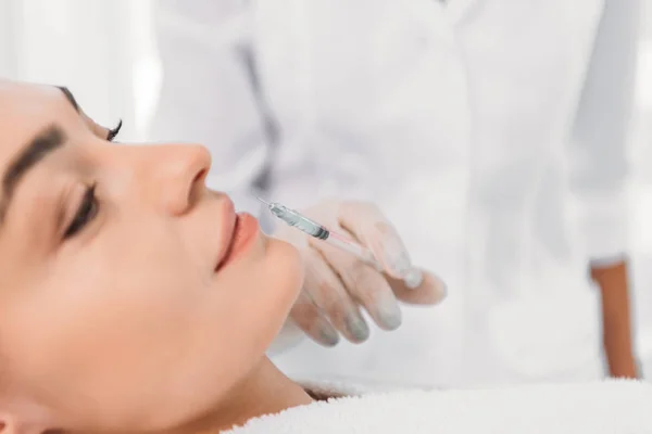 Plan recadré de cosmétologue en gant de latex avec seringue faisant injection de beauté à belle femme dans le salon de spa — Photo de stock