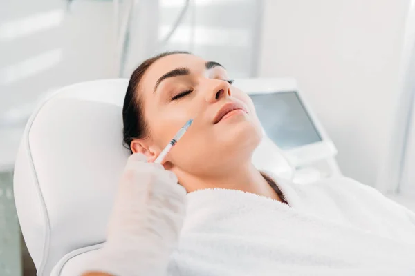 Cropped shot of cosmetologist in latex glove with syringe making beauty injection to beautiful woman in spa salon — Stock Photo
